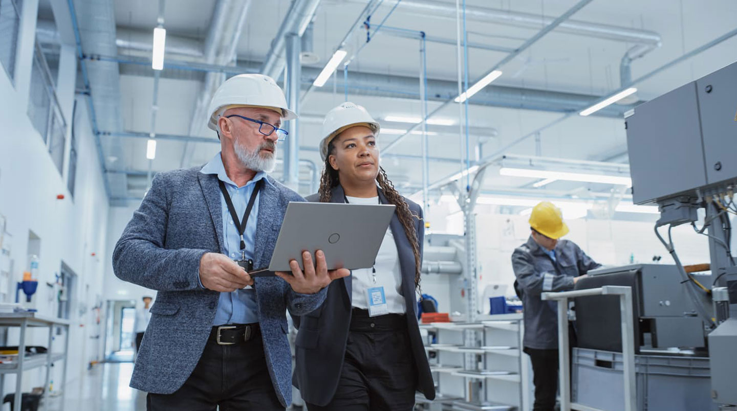 Technicien auditeur énergétique inspectant tableau électrique industriel avec appareil de mesure, dirigeant son regard vers l'installation analysée